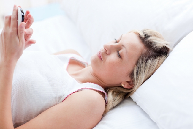 Surrogate mother relaxing in bed on phone